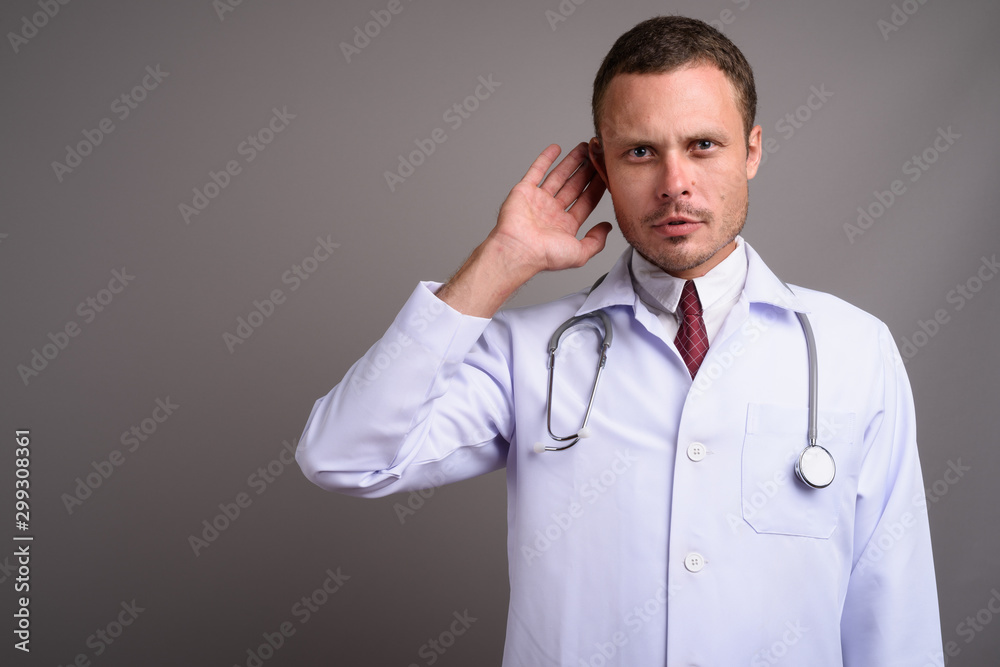 Portrait of handsome man doctor against gray background