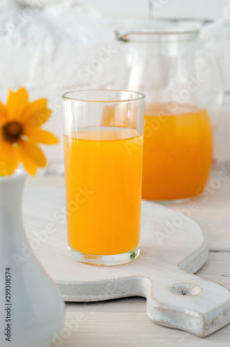 Apricot juice in glass and vase with flower