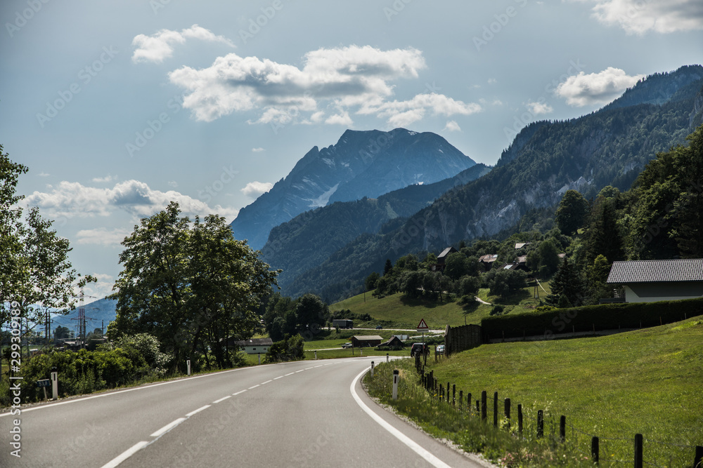 Autobahn or highway with a bridge in the mountains with clear marking surrounded by vibrant green trees under blue sky. Mountain in the background. The Alps, Austria