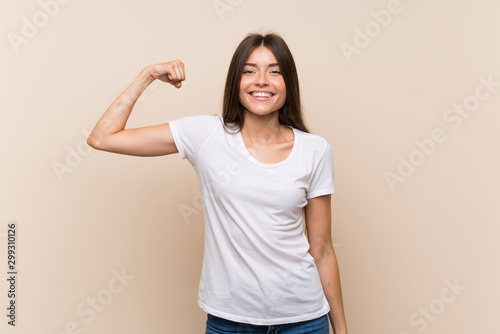 Pretty young girl over isolated background doing strong gesture