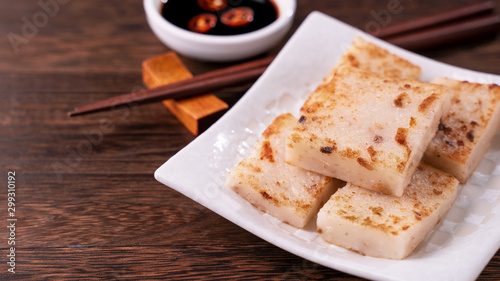 Delicious turnip cake, Chinese traditional local dish radish cake in restaurant with soy sauce and chopsticks, close up, copy space. photo