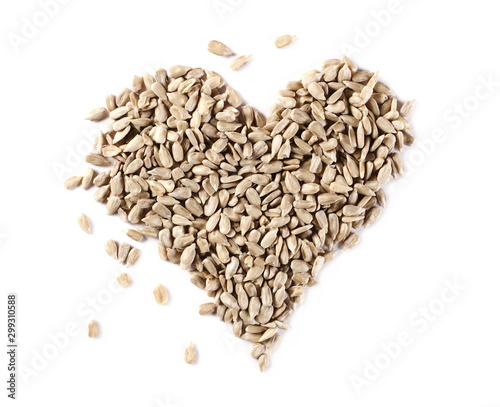 Peeled sunflower seeds arranged in heart shape isolated on white background, top view