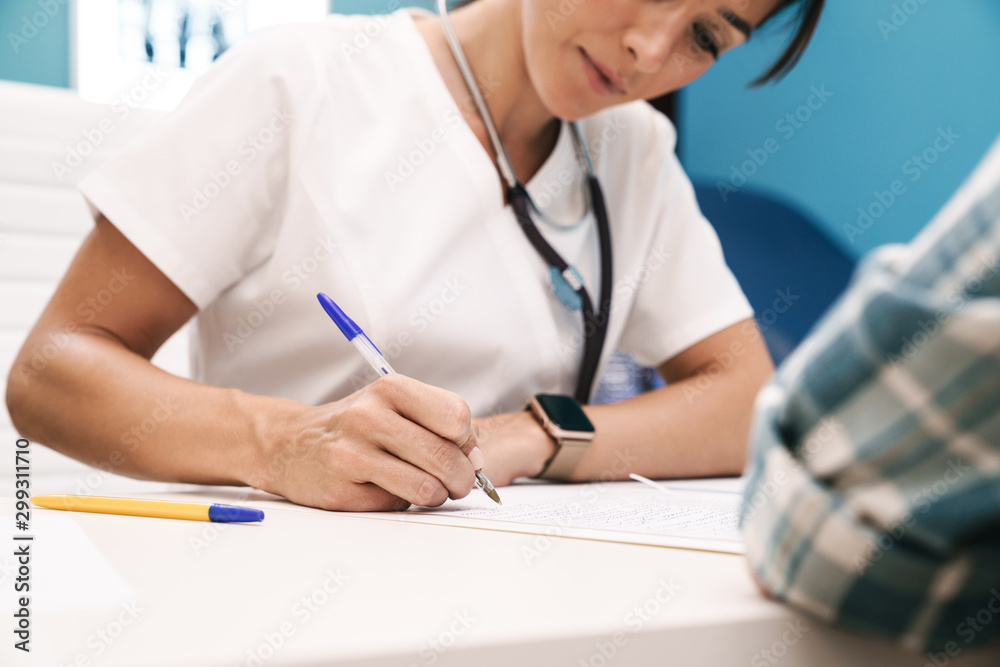 Doctor writing the recipe for patient in hospital at the table. Doctor writing the recipe for patient in hospital at the table.