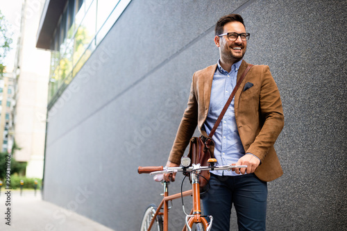 Happy young stylish businessman going to work by bike photo