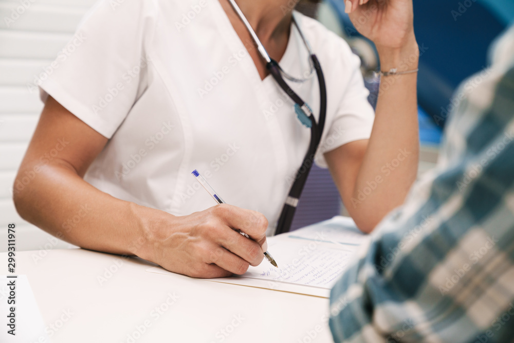 Doctor writing the recipe for patient in hospital at the table. Doctor writing the recipe for patient in hospital at the table.