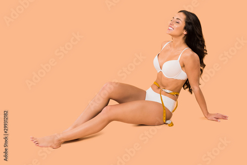 beautiful woman in underwear smiling and sitting on beige