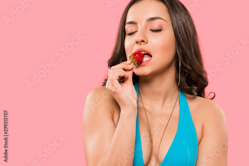 sexy woman eating tasty strawberry isolated on pink