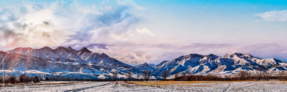Bright sunlight through the clouds against the backdrop of a breathtaking evening, morning sky and snowy mountain peaks at sunset, dawn. panorama, natural composition