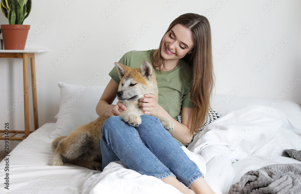 Young woman and Akita Inu dog in bedroom decorated with houseplants Young woman and Akita Inu dog in bedroom decorated with houseplants