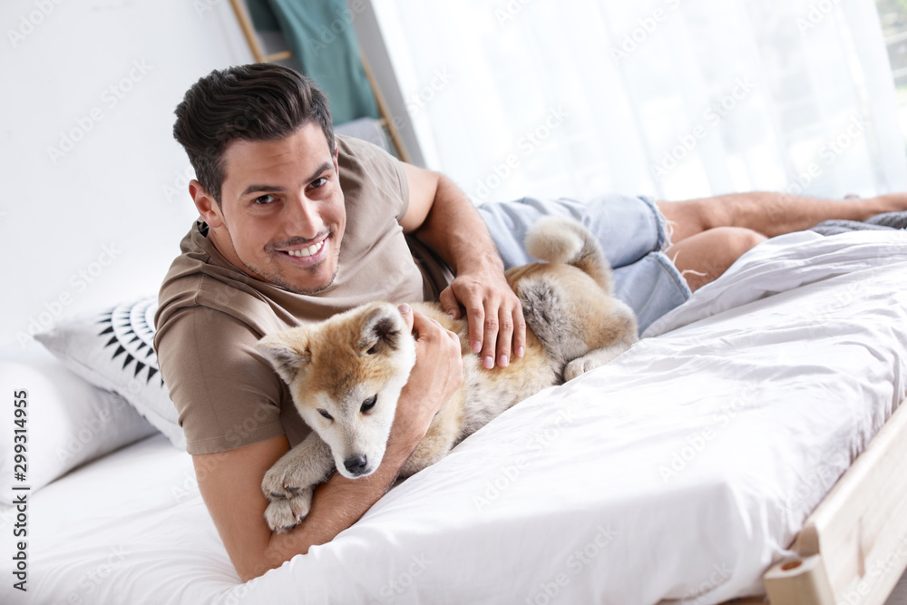 Man and adorable Akita Inu dog in bedroom Man and adorable Akita Inu dog in bedroom