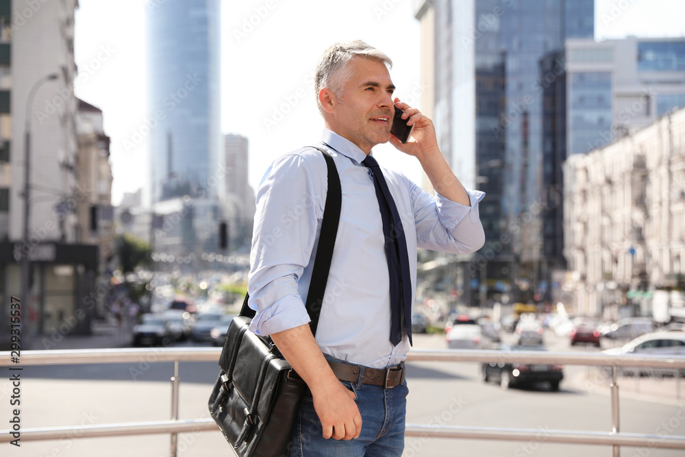 Handsome businessman talking by mobile phone in city Handsome businessman talking by mobile phone in city