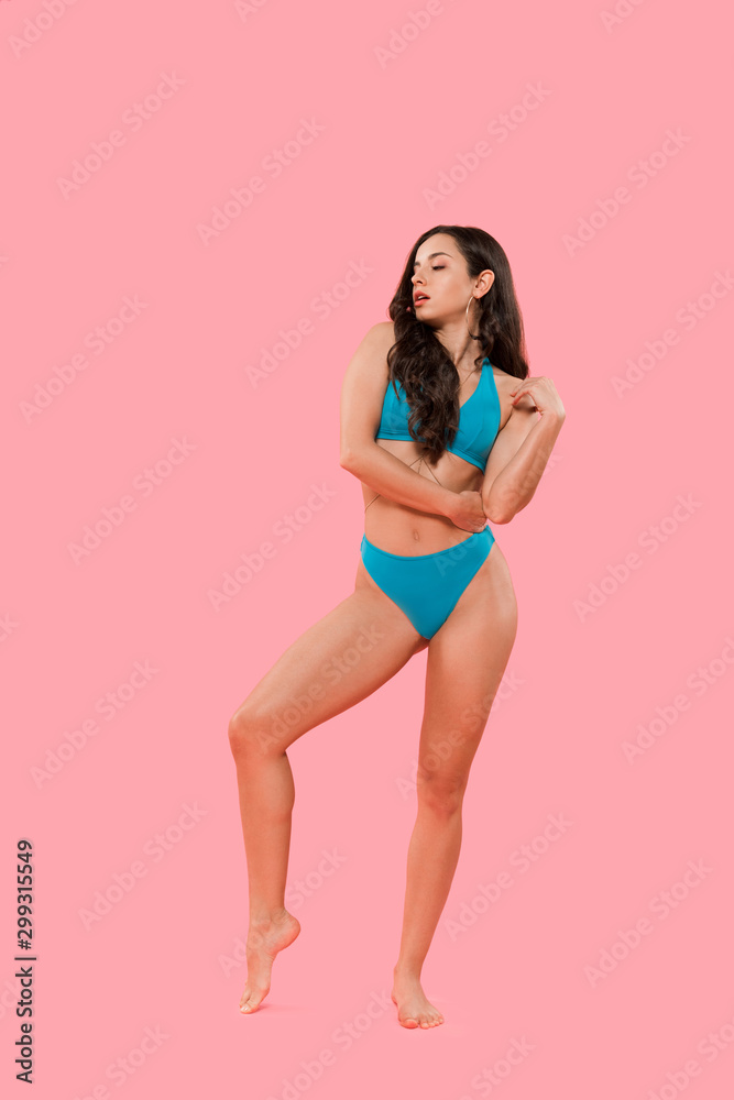 sexy woman in blue swimsuit standing isolated on pink