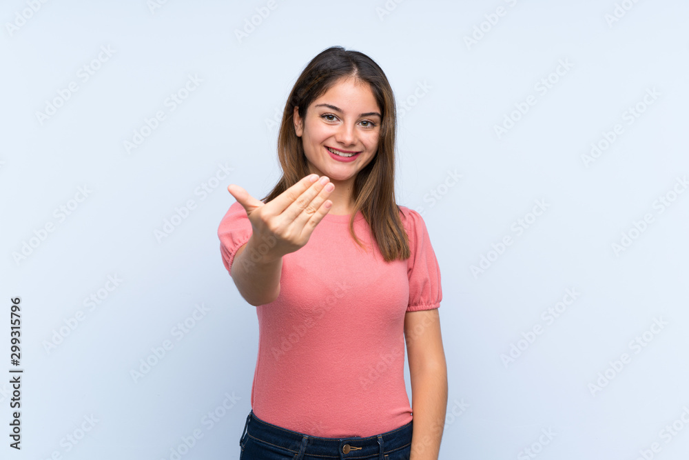 Young brunette girl over isolated blue background inviting to come Young brunette girl over isolated blue background inviting to come