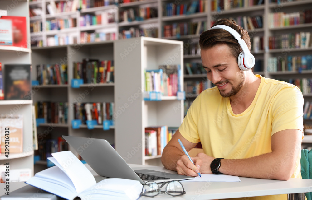 Young man studying at table in modern library Young man studying at table in modern library