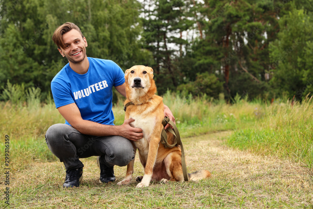 Male volunteer with homeless dog at animal shelter outdoors Male volunteer with homeless dog at animal shelter outdoors