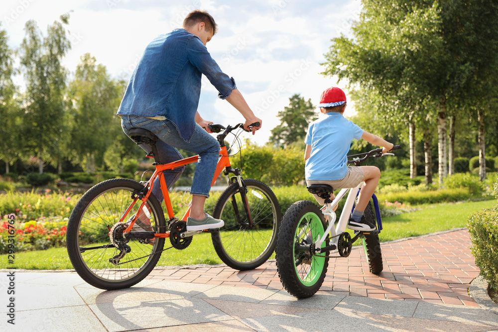 Fototapeta premium Dad and son riding modern bicycles outdoors