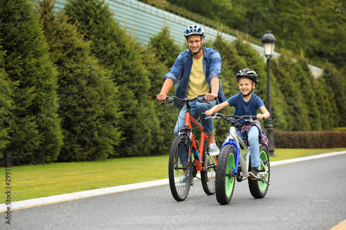 Foto Dad and son riding modern bicycles outdoors