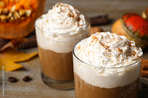 Glasses with tasty pumpkin spice latte on wooden table, closeup