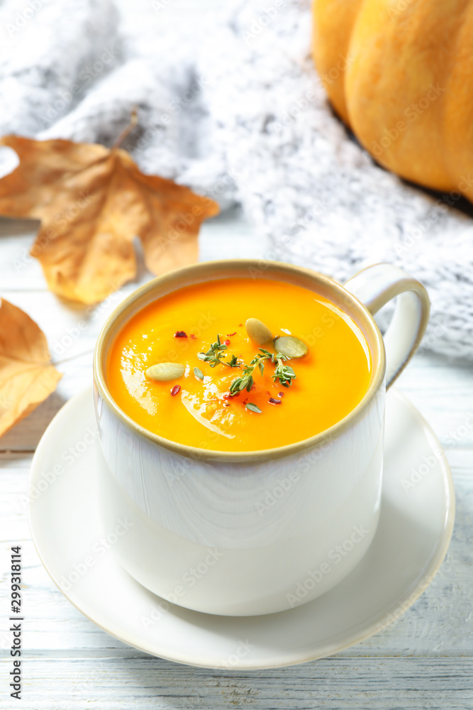 Delicious pumpkin soup in cup on white wooden table Delicious pumpkin soup in cup on white wooden table