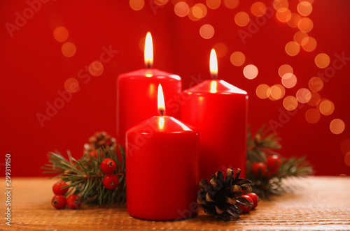 Beautiful Christmas composition with burning candles on wooden table against blurred lights
