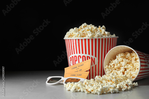 Popcorn, cinema tickets and 3d glasses on grey table. Space for text