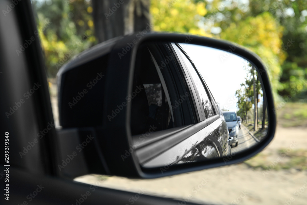 Closeup of car side rear view mirror on sunny day