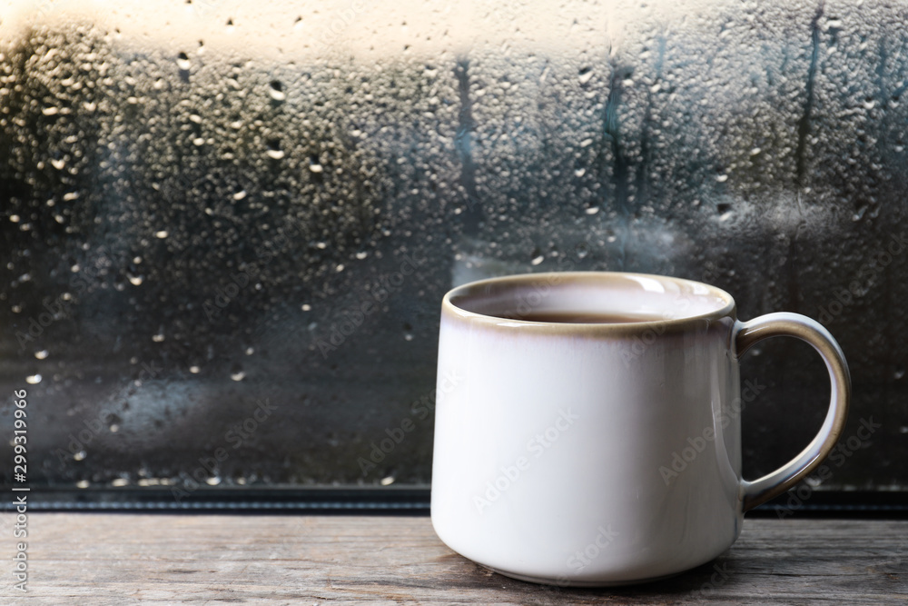 Cup of hot tea on wooden window sill. space for text. Rainy weather - obrazy, fototapety, plakaty 