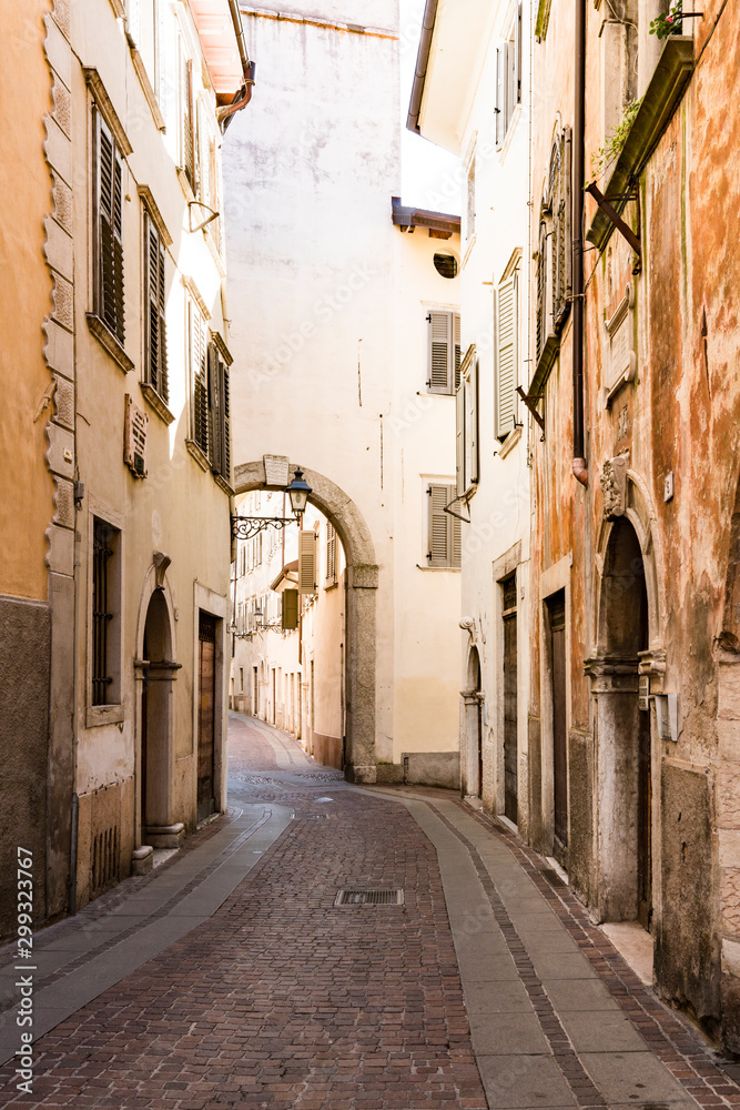 Narrow street with gate, tower in Rovereto, Italy