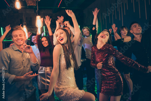 Photo of big company of students having entered night club to have fun and dance together with excited facial expressions and lights shining above