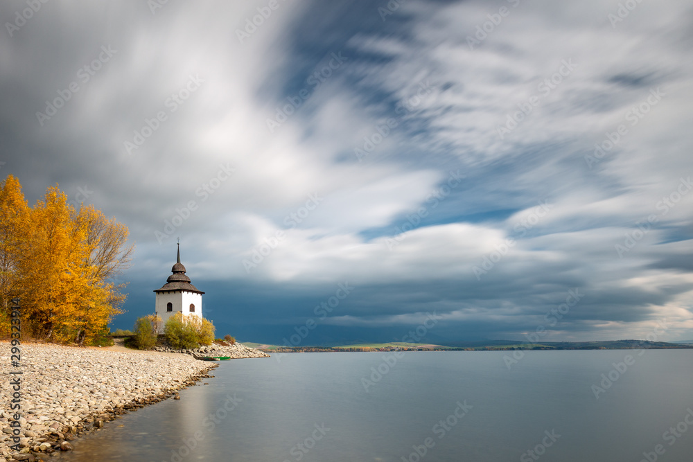 Church Tower of Virgin Mary at the shore of The Liptovska Mara dam in the morning light at autumn, the area of Liptov in Slovakia, Europe. Long time exposure used.