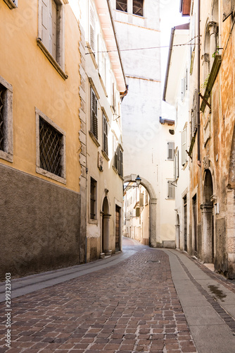 small street with brown orange houses and civil tower, gate.  Rovereto, Italy © Corinne