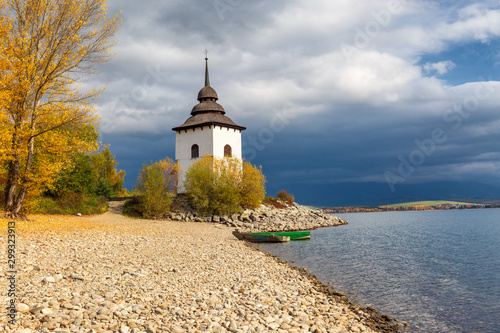 Church Tower of Virgin Mary at the shore of The Liptovska Mara dam in the morning light at autumn, the area of Liptov in Slovakia, Europe. photo