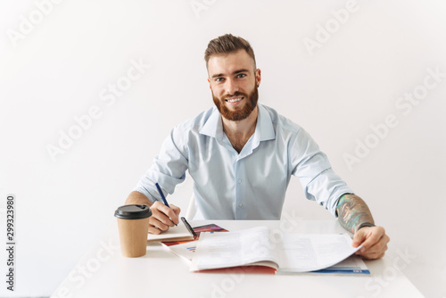 Image of brunette man sitting at table and studying with exercise books