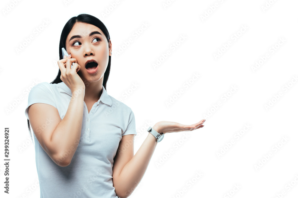 shocked attractive asian girl with open mouth talking on smartphone isolated on white