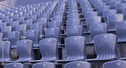  Gray stands in an empty stadium on a sunny day. Style and precision. Gray seats with numbers.