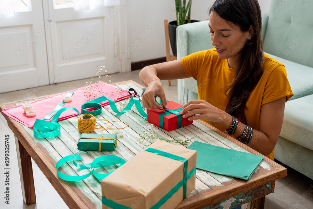 Woman wrapping handmade craft gifts on the table at home