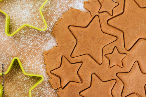 Dough for gingerbread cookies on a table sprinkled with flour. Cutting cookies in the shape of stars. 