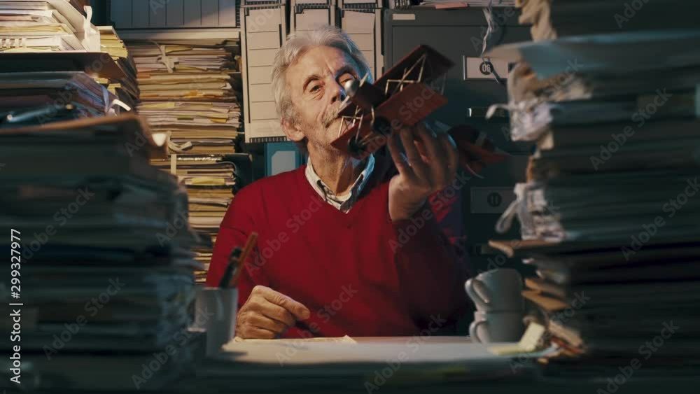 Funny senior office worker playing with a toy airplane Funny senior office worker playing with a toy airplane