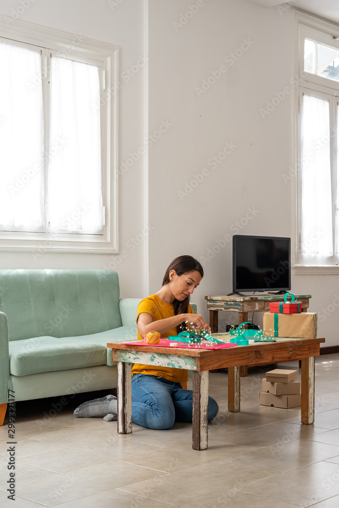 Woman wrapping handmade craft gifts on the table at home Woman wrapping handmade craft gifts on the table at home