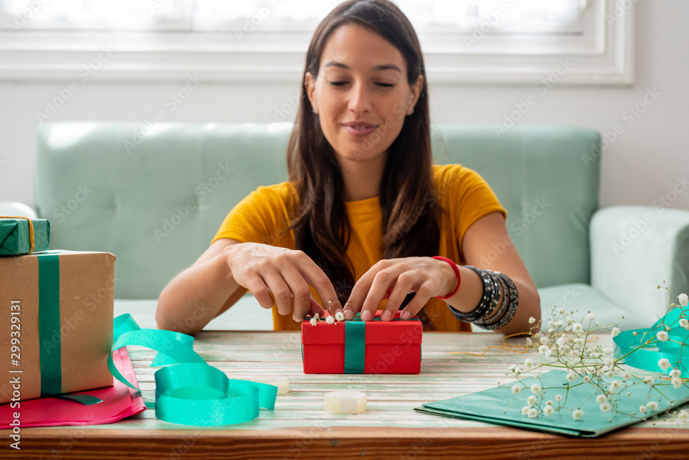 Fototapeta premium Woman wrapping handmade craft gifts on the table at home
