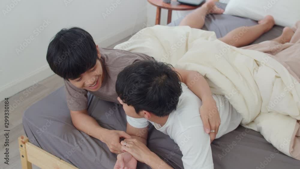 Handsome Asian gay couple talking on bed at home. Young ...