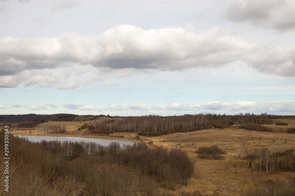 Panorama of the spring landscape with a lake and hills with copses. Izborsk, Pskov region, Russia.