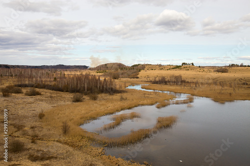 Panorama of the spring landscape with a lake and hills with copses. Izborsk, Pskov region, Russia. © 1802185