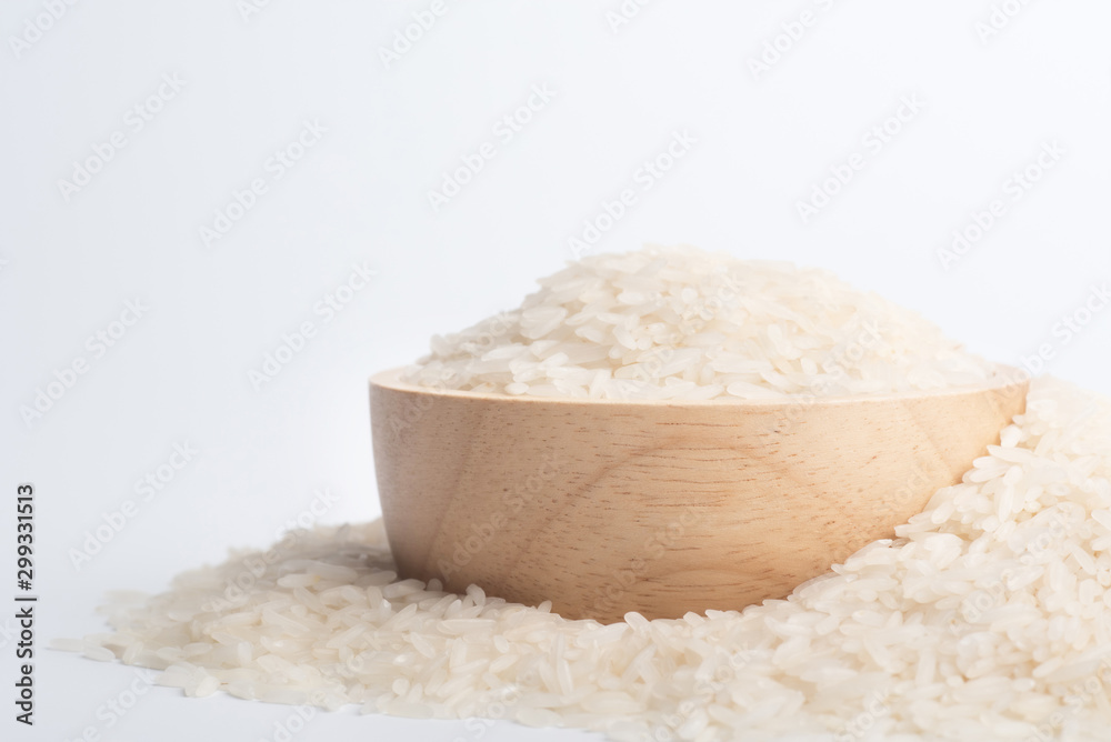 Clean rice grain in a brown wooden bowl on a white background. Clean rice grain in a brown wooden bowl on a white background.