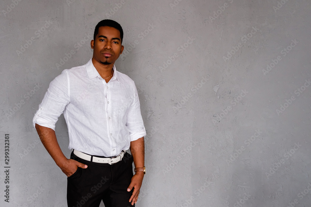 Successful handsome confident African American businessman posing against the background of a gray wall in formal clothes. Concept of entrepreneurial successful young business people. Copyspace