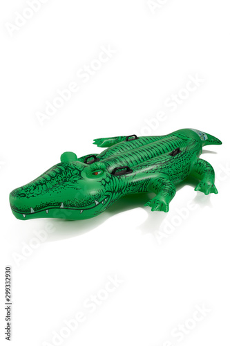 IInflatable mattress in the form of a crocodile made of durable material for fun and comfortable rest on the water. The mattress has four grips. The photo is taking on a white background.
