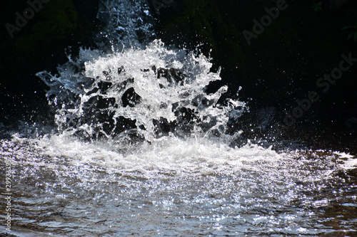 Close-up of water flowing. Dark background. The water eddies forms white scum. 