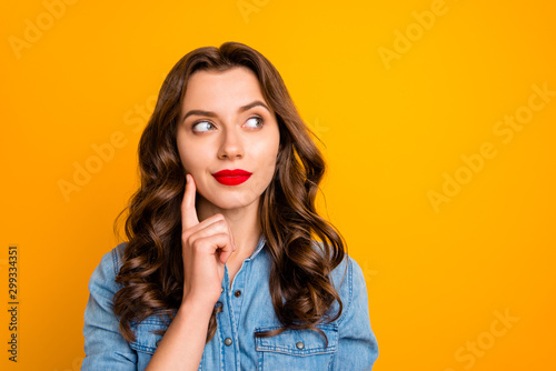 Photo of curly wavy trendy pensive youngster contemplating empty space above her isolated over yellow vivid color background photo