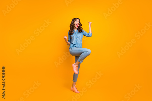 Full length body size photo of ecstatic overjoyed crazy cheerful pretty girl overjoyed about new information known shouting making fists expressing emotions isolated vivid color background
