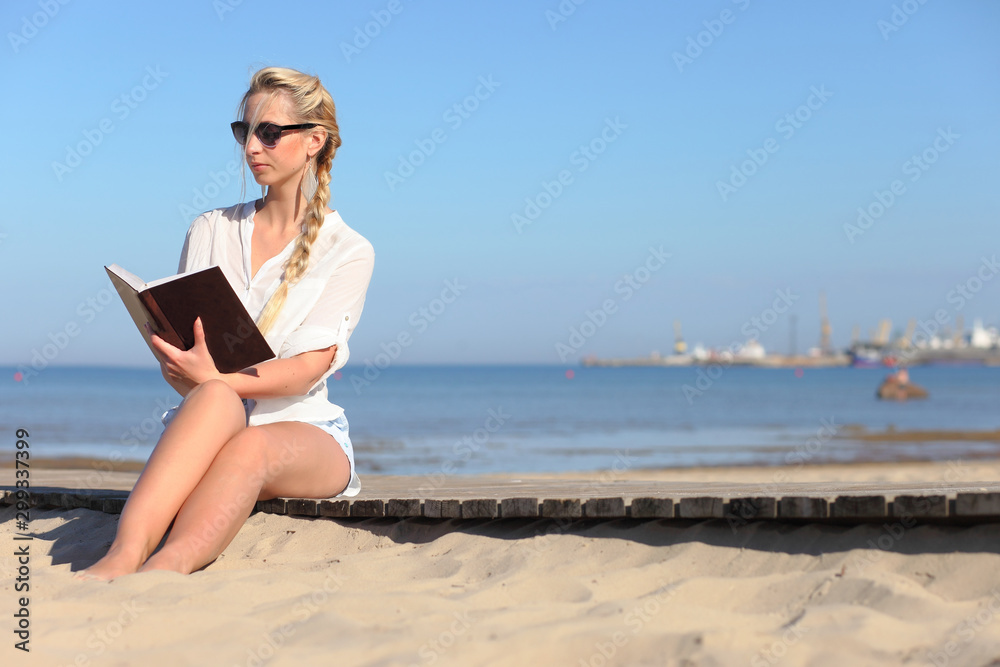 woman reads a book on the beach